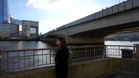 woman enjoying view of the shard and thames river by london bridge on a sunny day