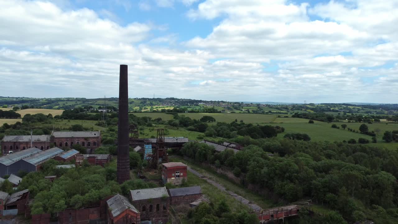 Forladte gamle tilgroede kulmine industrimuseumsbygninger, luftbillede med dollybevægelse til venstre, landskabsudsigt