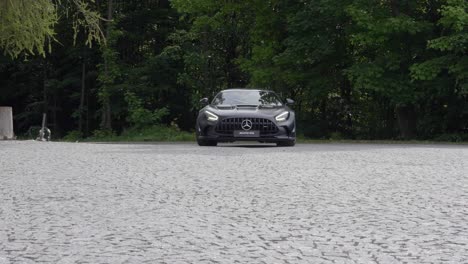 black sport car driving up a parking lot near an old castle, reveal shot