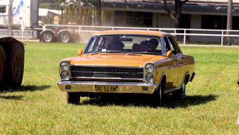 classic car driving across grass at event