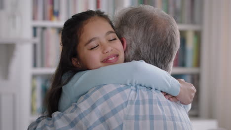 grandfather hugging granddaughter happy little girl embracing grandad enjoying affectionate hug from child sharing love gently holding grandparent at home