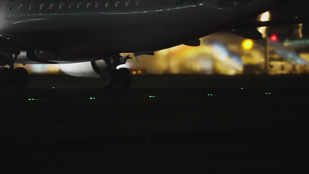 Parte inferiore di un aereo di linea di notte con le luci di mezzeria della pista