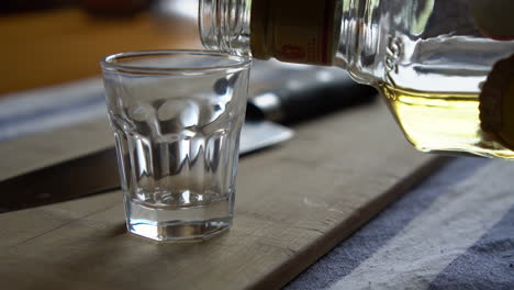 man pouring a shot of whiskey in a rustic environment similar to a distillery or a pub