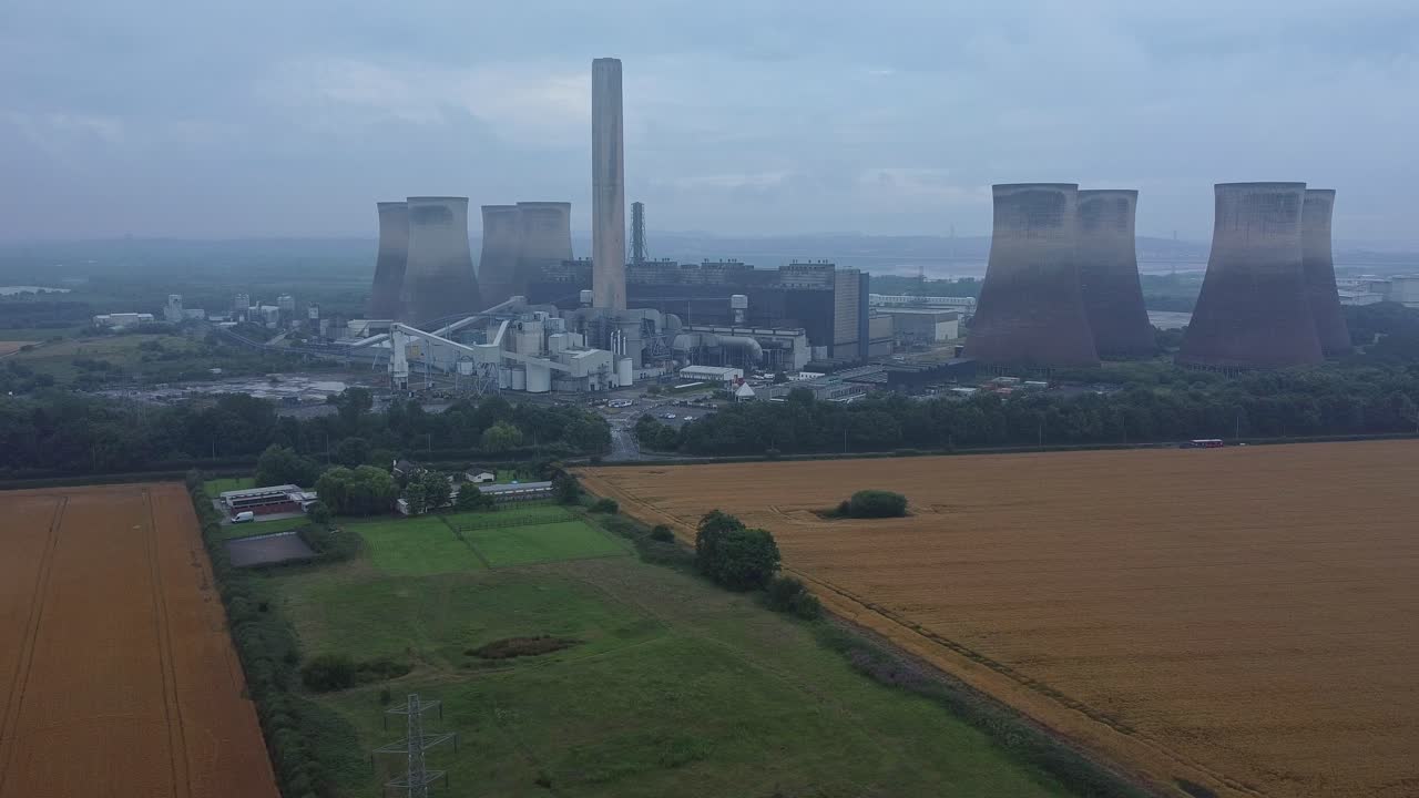 imponente torre de enfriamiento de hormigón estación de energía tierras de cultivo campo vista aérea amplia órbita derecha