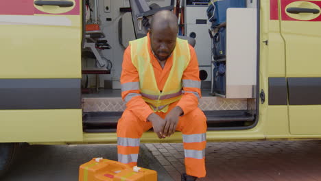 sorrowful black man on an ambulance next to a first aid kit