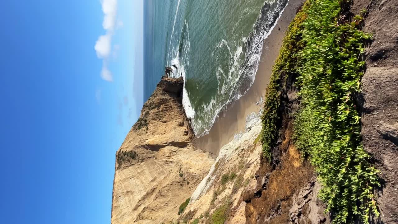 Splendida vista dalle scogliere, piccole onde sulla battigia e una giornata di sole