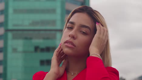 On-a-rooftop-in-Port-of-Spain,-Trinidad,-a-young-Hispanic-girl-wears-a-red-dress,-with-tall-buildings-behind-hervfacial-close-up