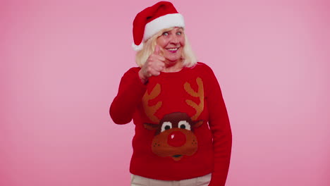 Grandmother-wears-red-New-Year-sweater-with-deers-raises-thumbs-up-agrees-with-something-good,-like