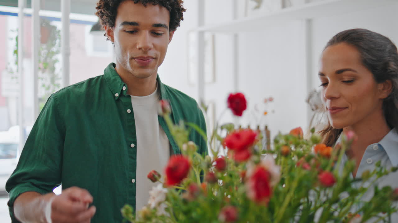 Blumenladenbesitzerin zeigt einen Blumenstrauß. Freundlicher afrikanischer Kunde kauft Blumen