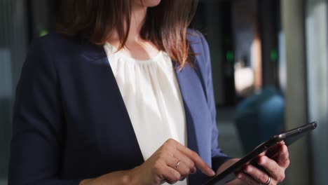 Portrait-of-smiling-caucasian-businesswoman-using-tablet-in-modern-office