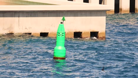 boya verde flotando cerca de una estructura de hormigón