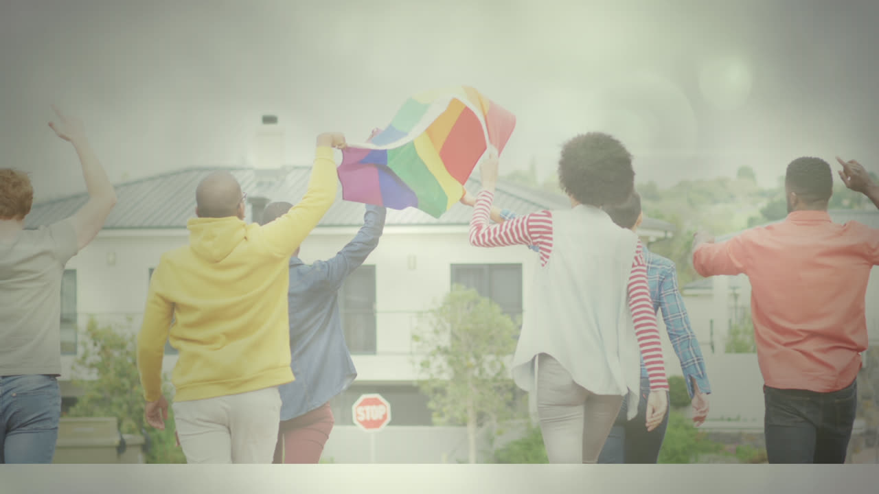 Diverse group of people holding rainbow flag while walking towards building