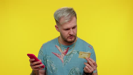 Tourist-man-using-credit-bank-card-and-smartphone-while-transferring-money-purchases-online-shopping