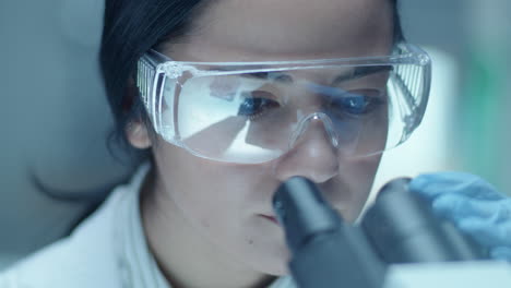 female microbiologist doing medical test with lab microscope