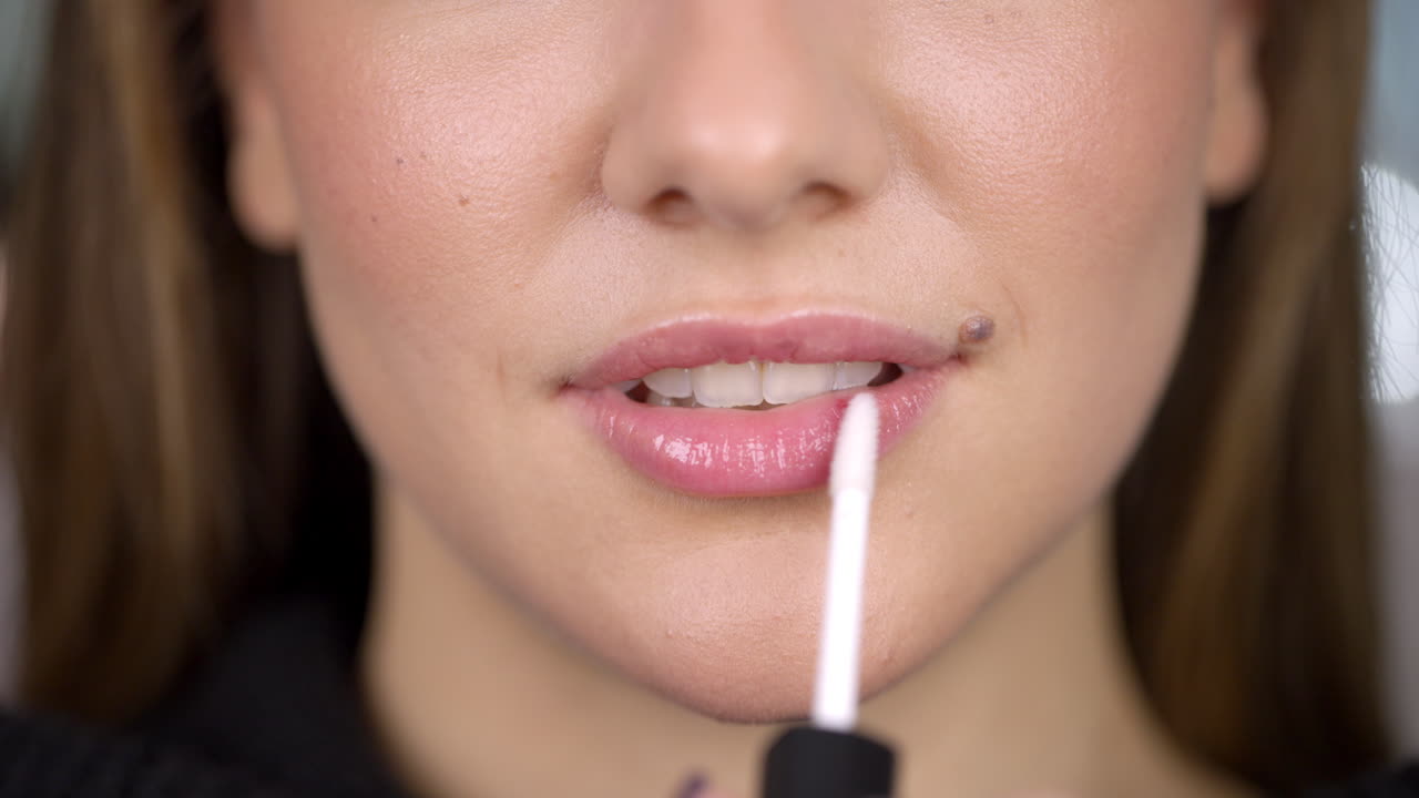 Close-up of a woman applying lip gloss