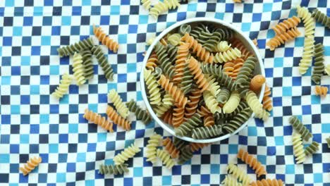 Bio-Fusilli-Trie,-Der-Auf-Rosa-Hintergrund-Verschüttet-Wird