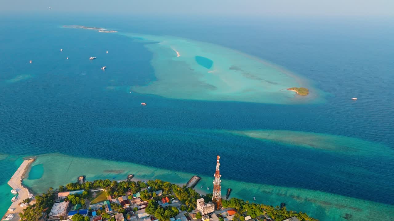 A stunning aerial drone view showcasing Rasdhoo Island surrounded by crystal-clear turquoise waters and vibrant coral reefs in the Maldives.