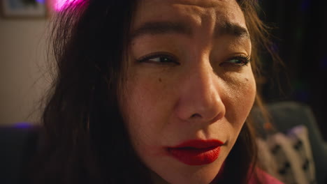 close up of confused woman sitting on sofa after drinking alcohol at house party suffering with hangover