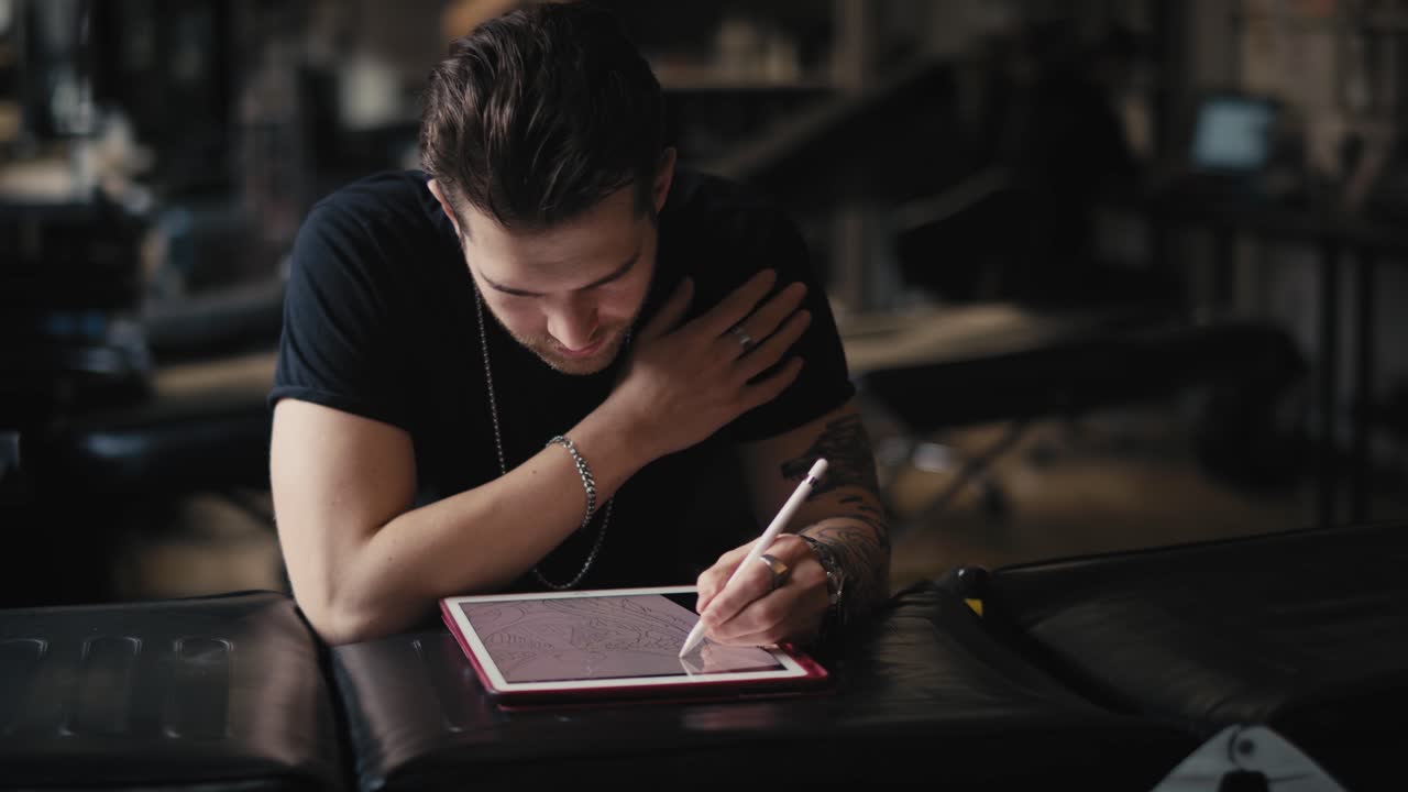 Tattoo artist  designing motifs on digital tablet.