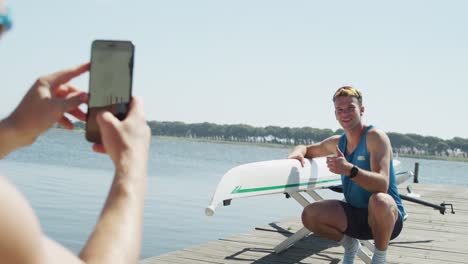 male rower taking picture of male rower next to the boat