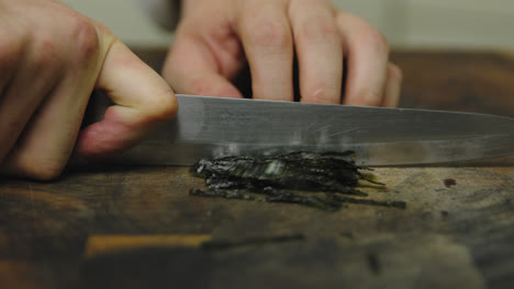 close up shot of male chef cutting seaweed on wooden board,slow motion