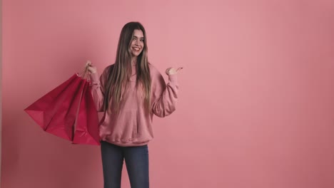 young woman holding shopping bags pointing aside
