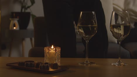 man planning romantic evening at home in lounge with wine chocolates and gift