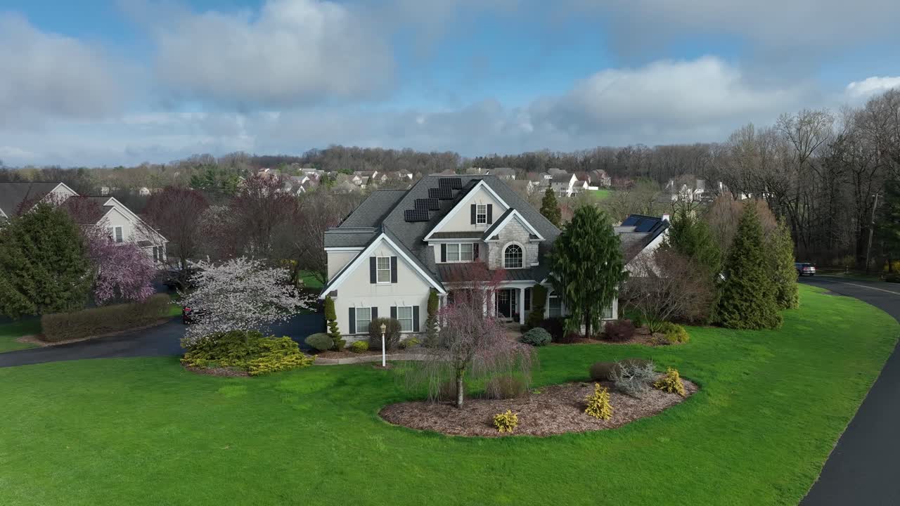 Two-story American suburban home with green lawn and flowering trees in a spacious neighborhood