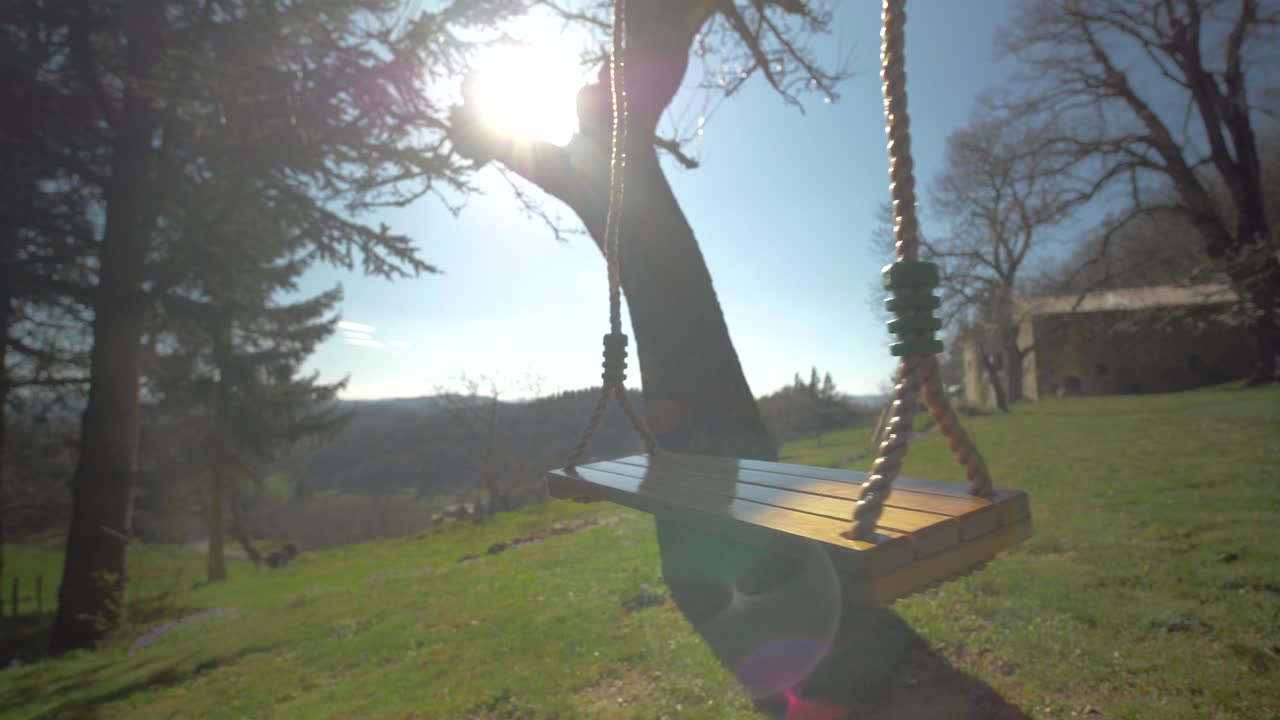 Close-up Of A Swing Hanging On A Tree Moving With The Wind Under The Sun In The Countryside In Slowmotion in a french garden in ard&egrave;che