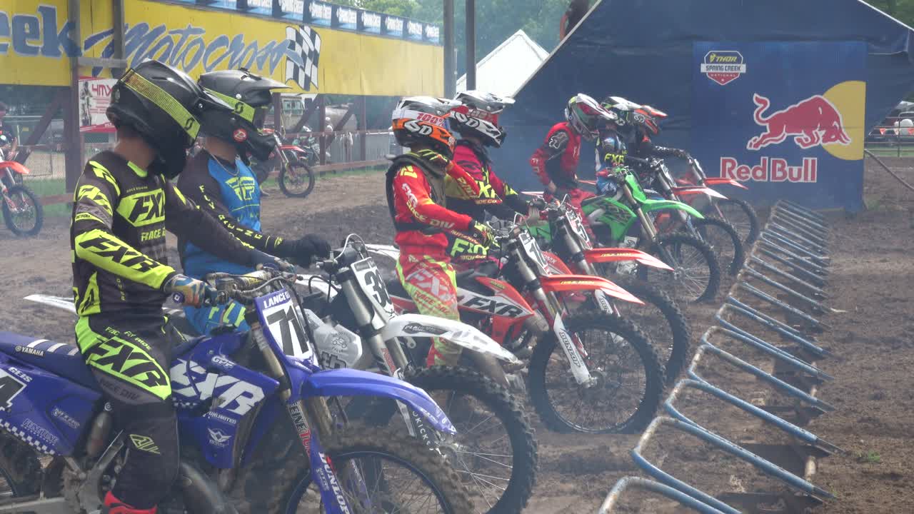 Pilotos de Motocross Acelerando os Motores no Portão de Partida Antes da Corrida