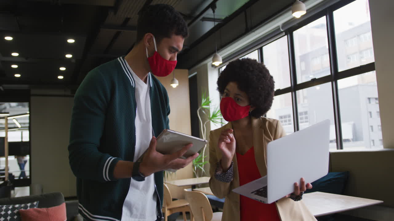 현대적인 사무실에서 노트북과 디지털 태블릿을 사용하는 다양한 비즈니스 사람들이 서 있습니다.
