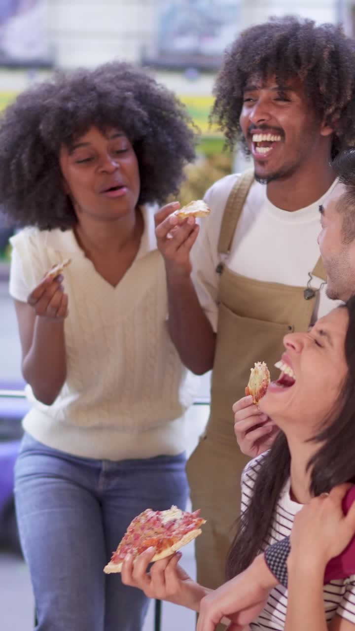 A group of diverse friends laughing and eating pizza together