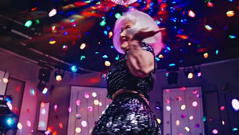 elderly woman with a stylish white wig and sparkling outfit dancing energetically at a vibrant disco party, celebrating active aging under colorful lights and confetti