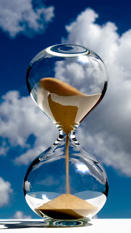 hourglass against a cloudy blue sky
