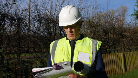 tracking shot of a serious architect building inspector looking at a building and writing on paperwork on a clip board