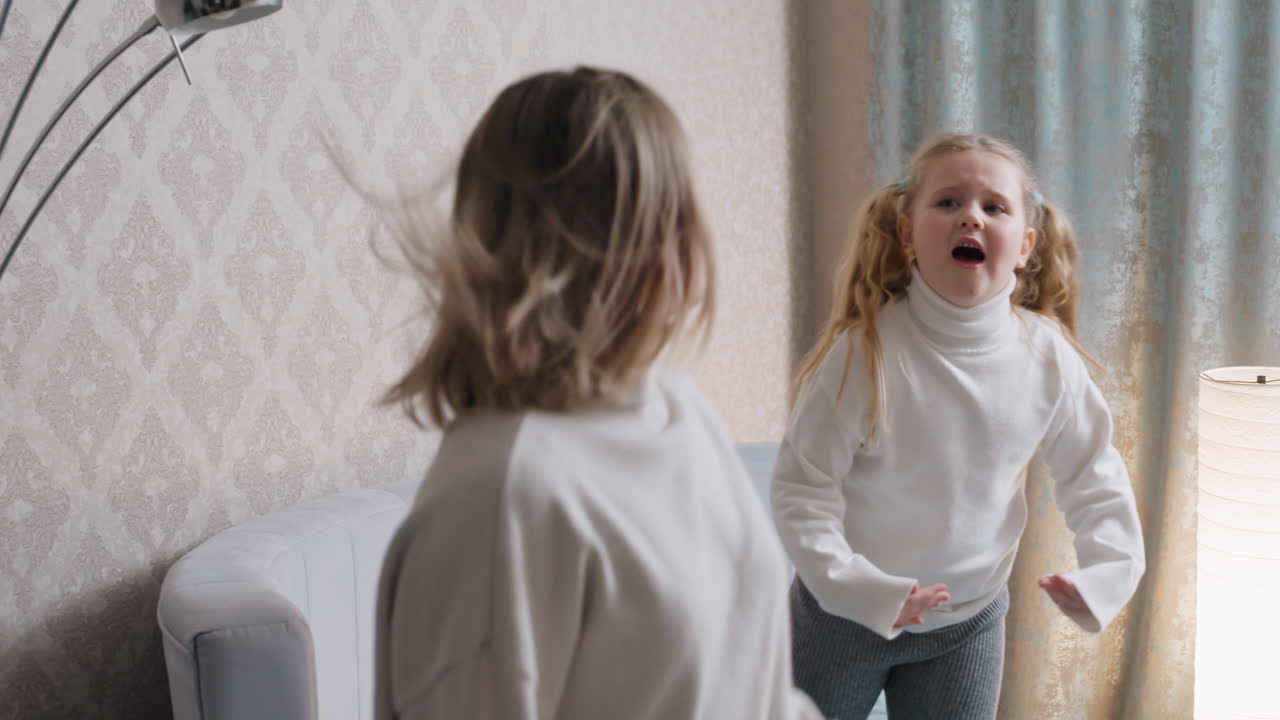 Mother and daughter in cozy white sweaters share energetic playful dance in bedroom, child with pigtails animatedly expressing joy while mother turns with movement, capturing happiness, bonding