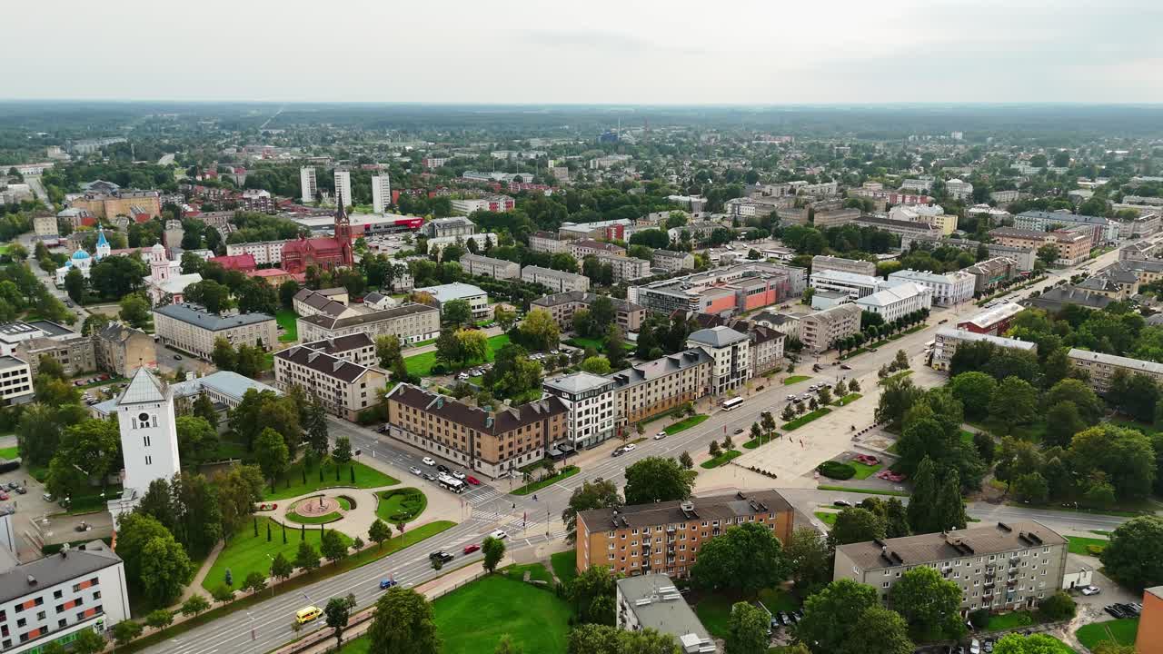 Drone footage showing a panoramic aerial view of Jelgava city, Latvia, with residential buildings, streets, and green areas