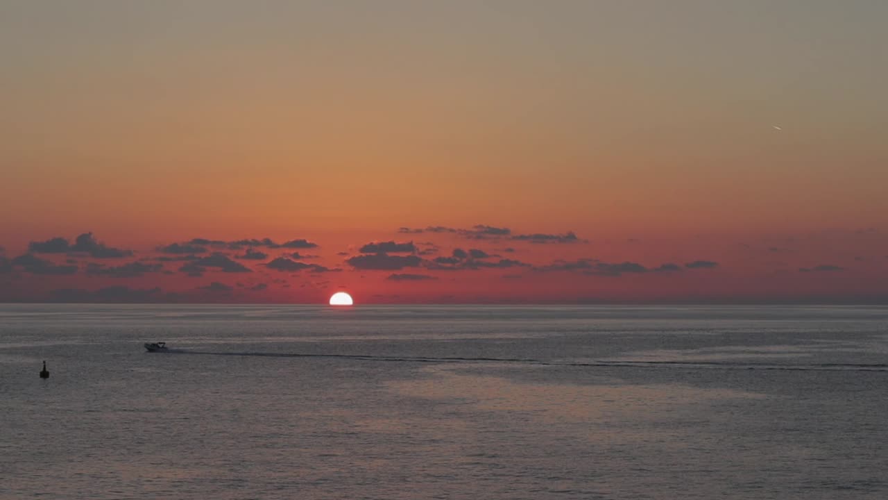 la colorida puesta de sol en el mar cuando el sol desaparece detrás del horizonte, con barcos deslizándose suavemente en el agua, encarnando la serenidad, la paz, el viaje y la exploración