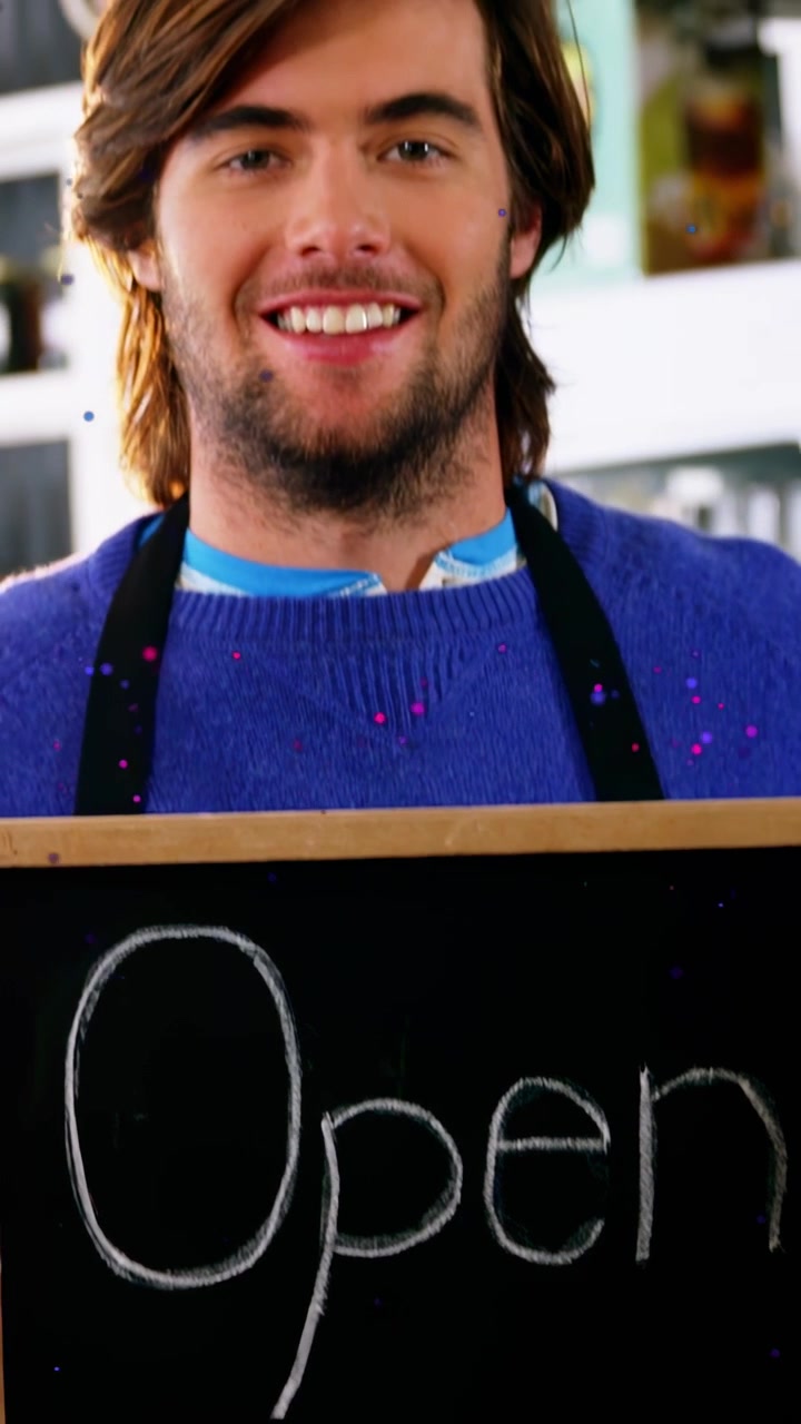 Vertical video: Camera pulling back, man raising sign and showing Open, inviting customers in deli