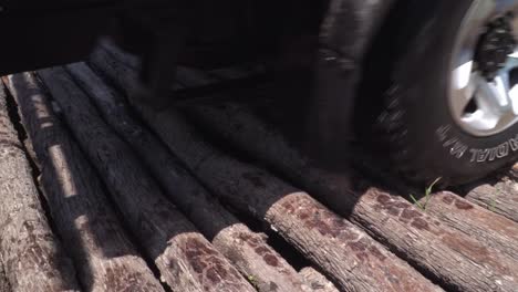 close up of a car passing a log bridge in the jungle