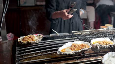 street vendor grilling oysters with toppings