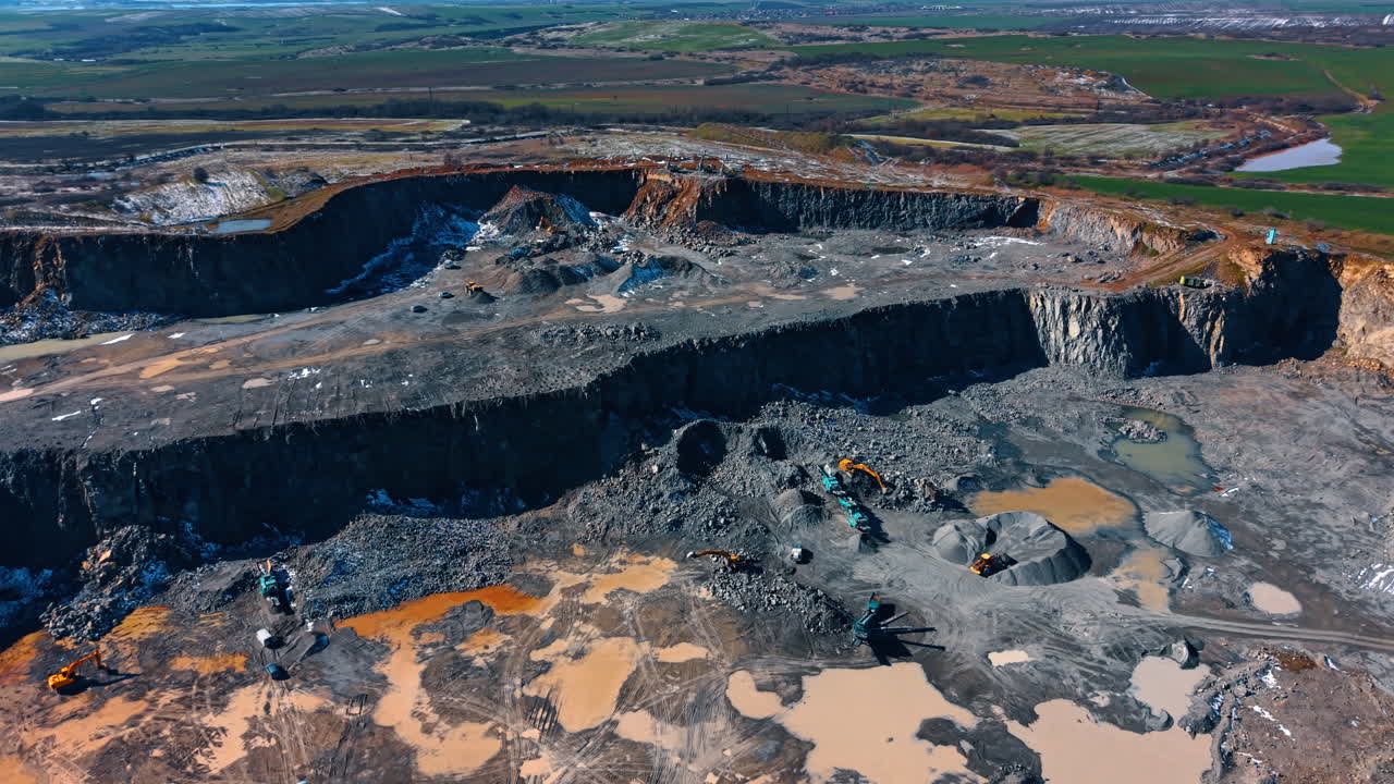 Mining site with machinery. Heavy machinery is working at a mining site surrounded by dirt and water during daylight in a rural area