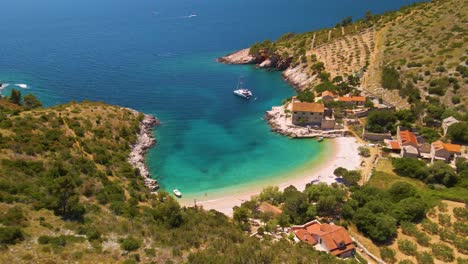 View-of-a-coastal-town-with-many-houses-with-red-roofs,-surrounded-by-the-sea-and-mountains-with-yachts-in-marina-bay-and-Bell-tower-with-fields-around