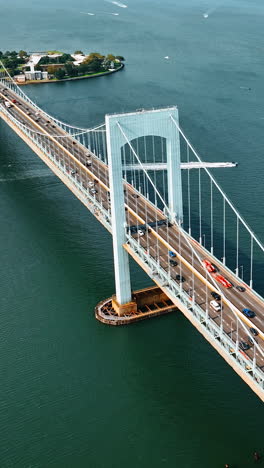 cars running quickly by the long suspension bridge on sunny day. top view of the throgs neck bridge and the east river with boats on. vertical video