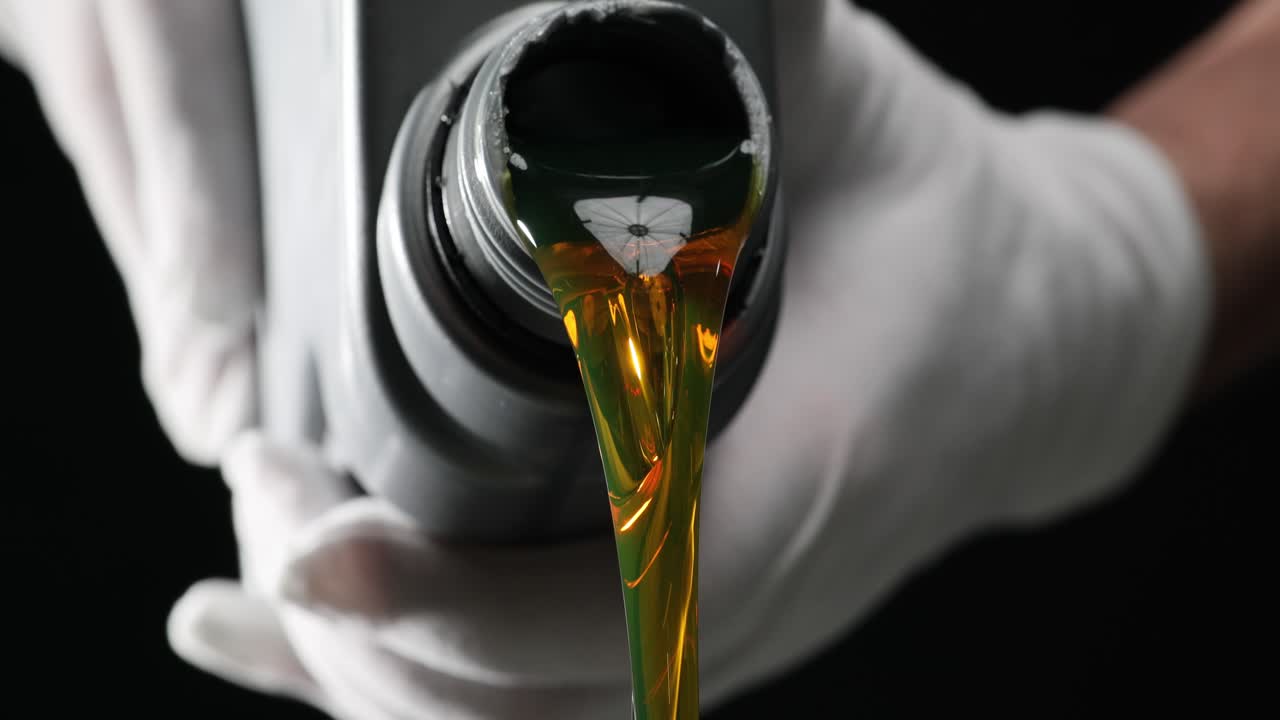 Person in rubber gloves pours car motor oil from bottle