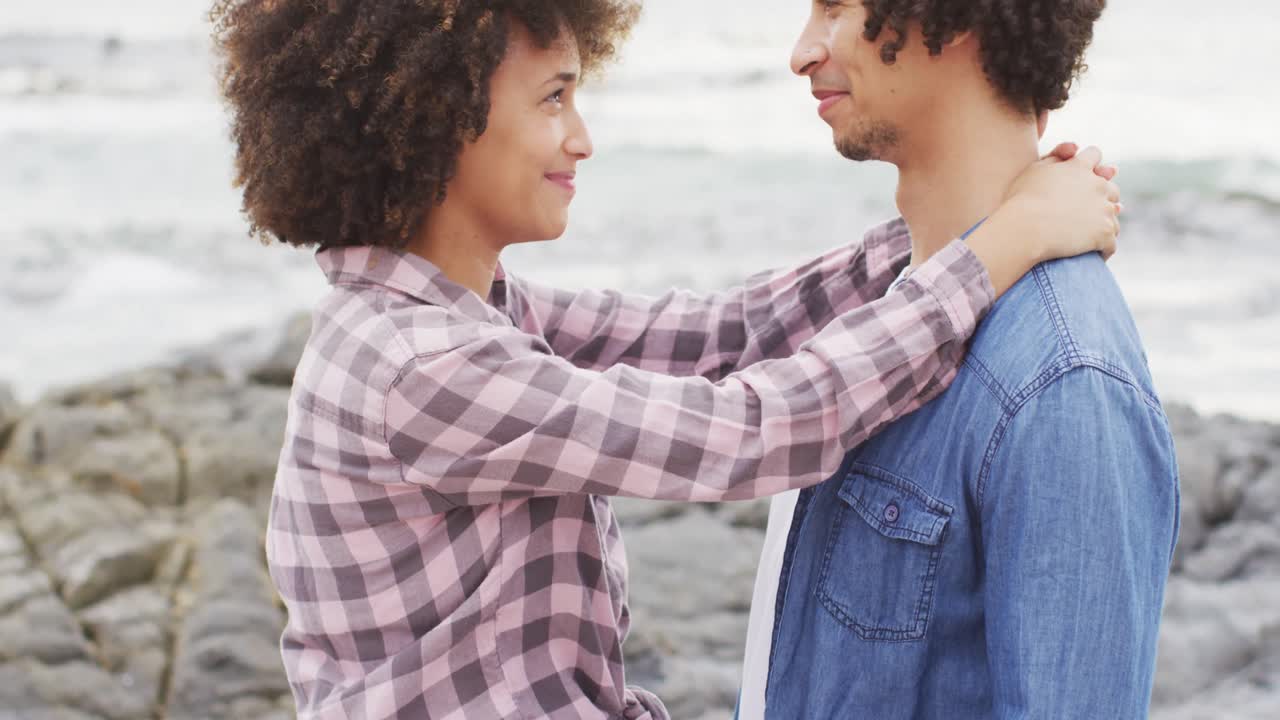 African american couple embracing each other on the rocks near the sea