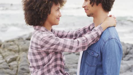 pareja afroamericana abrazándose en las rocas cerca del mar