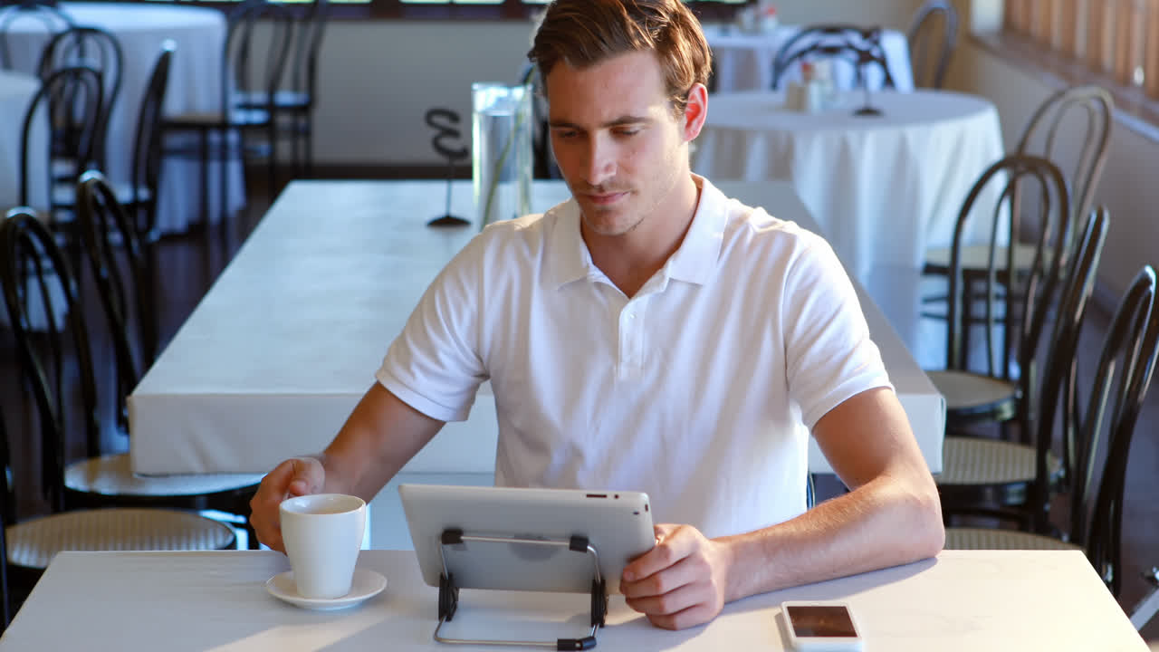 Man having cup of coffee and using digital tablet