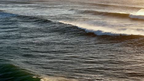 Golden-sunlight-reflecting-on-tumultuous-ocean-waves,-The-sea's-surface-glistening-at-sunset