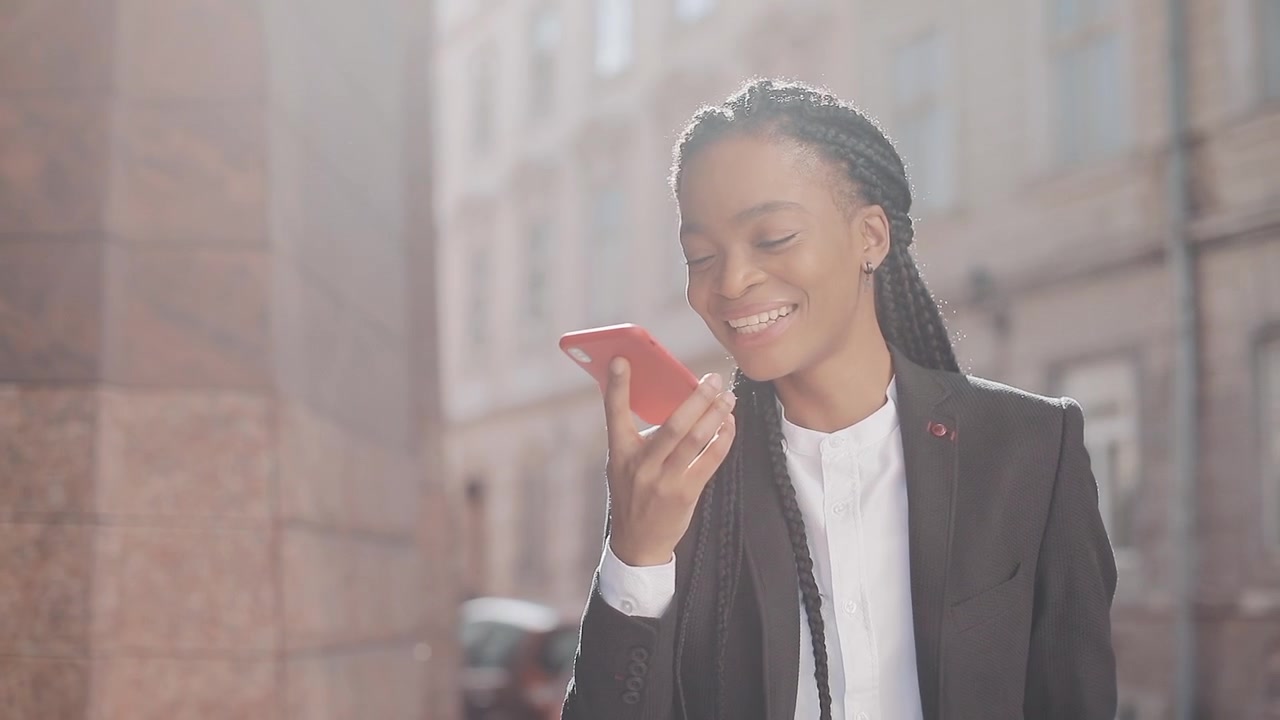 Donna d'affari sorridente che usa lo smartphone su una strada cittadina